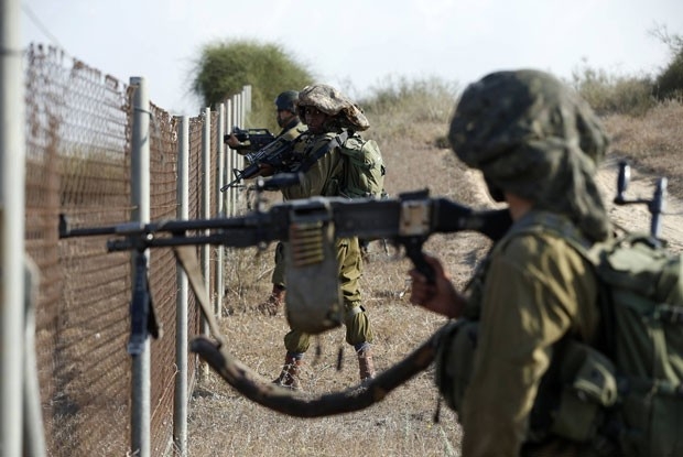 Soldados israelenses se posicionam ao lado de cerca na cidade de Sderot durante infiltração de militantes palestinos nesta segunda-feira (21) 