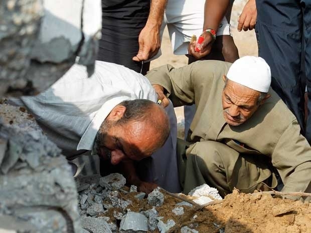 Equipes de resgate palestinas procuram vítimas em um prédio destruído por um ataque aéreo israelense em Rafah.