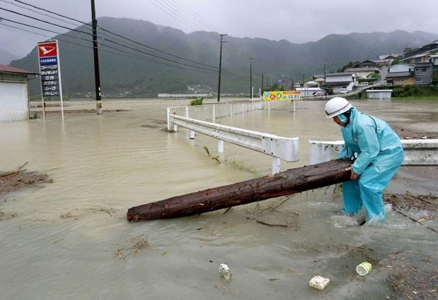 Japonês retira pedaço de árvore de Estrada inundada em Shingu neste sábado (10)