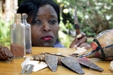 Mulher queniana diante dos instrumentos utilizados na Mutilação Genital Feminina (MGF).