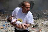 Homem segura bebê sobrevivente a bombardeio com barris explosivos em Aleppo. (Abdalrhman /Reuters)