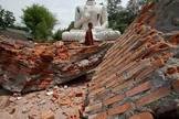 Budista caminha sobre escombros de terremoto em templo na Tailândia.