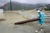 Japonês retira pedaço de árvore de Estrada inundada em Shingu neste sábado (10)