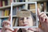Karen King exibe o papiro com trecho do "Evangelho da Esposa de Jesus", desmascarado após revelação do antigo proprietário. (Foto: Harvard Magazine)
