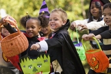 Crianças estendem suas sacolas para ganhar doces, durante festas do Halloween.