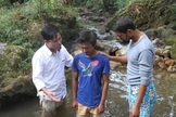 Pastor Lazrus e outro membro de sua equipe oram com jovem, antes de seu batismo, realizado em uma pequena cachoeira da região. (Foto: Levitas Nepal)