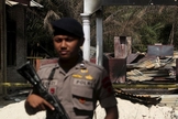 Policial segura rifle enquanto fica de guarda em frente a uma igreja queimada em Suka Makmur Village, em Aceh, Indonésia