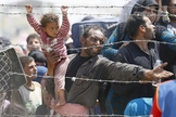 Refugiado sírio segura sua filha, enquanto tenta cruzar a fronteira da Turquia (Foto: Reuters)