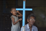 Homem e criança de família cristã olham pela janela de sua casa nos subúrbios de Yangon, em Myanmar. (Foto: Reuters/Damir Sagolj)