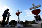 Mulher escreve uma mensagem em uma cruz em honra daqueles que foram mortos na boate gay 'Pulse', em Orlando. (Foto: Reuters)