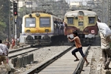 Imagem ilustrativa. Jovem atravessa trilho diante de um trem em funcionamento, em Mumbai, na Índia. (Foto: Reprodução)