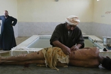Imagem ilustrativa. Homem preparando o corpo para um enterro muçulmano em Najaf, no Iraque. (Foto: João Silva/The New York Times)