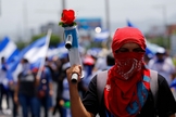 Manifestante exibe morteiro caseiro com uma flor durante marcha em Manágua, na Nicarágua. (Foto: Reuters/Oswaldo Rivas)