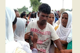O pai de Anjali Masih sendo confortado por vizinhos. (Foto: WWM)