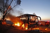 Ônibus em chamas depois de ser atingido por um foguete disparado da Faixa de Gaza, perto do kibutz de Kfar Aza. (Foto: Menahem Kahana/AFP)