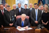 Donald Trump é cercado por líderes religiosos e legisladores no Salão Oval, ao assinar lei de ajuda humanitária. (Foto: Casa Branca/Shealah Craighead)