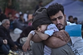 Refugiado sírio segura o filho nos braços em campo, na Turquia. (Foto:  AP/Lefteris Pitarakis)