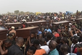 Homens carregam caixões em velório coletivo, após massacre na Nigéria. (Foto: Independent)