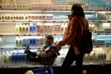 Mulher faz compras com bebê usando máscara em Pequim, em meio à epidemia de coronavírus na China. (Foto: Tingshu Wang/Reuters)