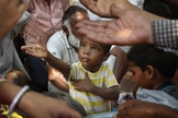 Criança estende a mão para receber comida em Nova Delhi, na Índia. (Foto: AP/Manish Swarup)