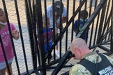 O soldado Dan Otterson (de farda) se ajoelhou, enquanto o garoto de 5 anos orou por ele, do outro lado da cerca. (Foto: Facebook)