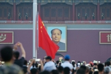 Visitantes acompanham uma cerimônia de hasteamento da bandeira com a imagem de Mao Tsé Tung ao fundo, na praça Praça da Paz Celestial, em Pequim, em julho de 2018. (Foto: CHINA STRINGER NETWORK/REUTERS/Newscom)