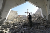 Um membro das forças árabes-curdas da Síria coloca uma cruz nos escombros antes de uma celebração de Natal na Igreja Católica Armênia dos Mártires, no centro da cidade de Raqa, leste da Síria, em 26 de dezembro de 2017. (Foto: DELIL SOULEIMAN / AFP)
