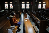 Mulher sentada no banco de uma Igreja Católica vazia em Des Moines, em Iowa, nos EUA. (Foto: Charlie Neibergall/Associated Press)