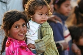 Garota síria segura bebê no colo, em campo de refugiados. 