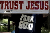 "Confie em Jesus", afirma cartaz, em inglês, durante ação de evangelismo. (Foto: Reuters)