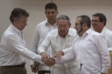 Presidente da Colômbia Juan Manuel Santos e o líder das FARC Timoleón Jiménez cumprem ato simbólico para acordo de paz, na frente do presidente cubano Raúl Castro (Foto: AP Photo / Desmond Boylan)