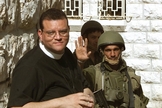 Um soldado israelense (R) recebe o Rev. Andrew White, o "vigário de Bagdá", enquanto ele tenta visita a Igreja da Natividade, em Belém, no dia 14 de abril de 2002. (Foto: Reuters/Oleg Popov)