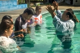 Pastor faz oração durante batismo de novos convertidos, em país da Ásia. (Foto: Christian Aid Mission)