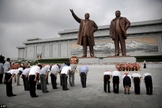 Norte-coreanos curvam-se diante das estátuas de bronze dos falecidos líderes Kim Il Sung e Kim Jong Il no Grande Monumento da Colina Mansu. (Foto: AP)