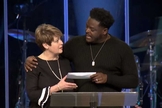 O pastor Derwin Gray entrega doação para Julie Walters, do Centro de Enriquecimento das Mulheres. (Foto: Reprodução/Facebook)