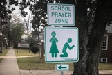 Placas com versículo bíblico convidam pais e alunos à oração. (Foto: Reprodução/CBN News)