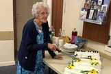 Marion Needham corta o bolo de aniversário preparado em sua homenagem por muitos amigos da igreja para marcar seu 100º aniversário. (Foto: Reprodução/Barnabas Fund)