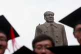 Graduados posam para foto em frente à estátua do líder chinês Mao Tsé Tung após sua cerimônia de formatura na Universidade de Fudan, em Xangai. (Foto: Aly Song/Reuters)