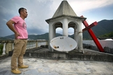 Líder de igreja permanece em pé no teto do templo, após o local ter sua cruz removida, na província de Zhejiang. (Foto:  Mark Schiefelbein/AP)