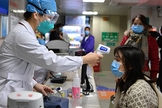 Profissional de saúde checa temperatura de mulher em um hospital de Fuzhou, na China. (Foto: Xinhua)