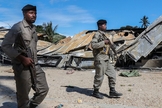 Soldados do exército moçambicano passam por um prédio destruído por insurgentes ligados ao Estado Islâmico em Palma, Moçambique. (Foto: João Relvas/EPA/Shutterstock)