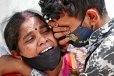 Mulher chora com seu filho depois que seu marido morreu devido à Covid-19 fora de um necrotério em Ahmedabad, na Índia. (Foto: Amit Dave / Reuters)