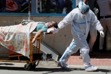Profissional de saúde leva paciente com Covid-19 em hospital de Nova Delhi, na Índia, neste sábado (24). (Foto: Adnan Abidi/Reuters).