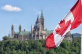 Bandeira canadense, com o parlamento ao fundo. (Foto: Reprodução / Shutterstock)