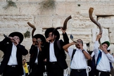 Judeus ultraortodoxos tocam o shofar enquanto os fiéis oram no Muro das Lamentações. (Foto: Reprodução / El País)