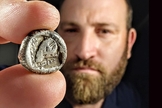 Yanniv David Levy, especialista em moedas da Autoridade de Antiguidades de Israel, segura a rara moeda de cerca de 2.500 anos. (Foto: Shai Halevi/Autoridade de Antiguidades de Israel)