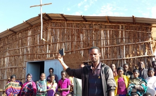 Em frente à igreja na África, cristãos seguram aparelho da Bíblia em áudio. (Foto: GHI)