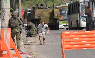 Homem se abaixa com medo de tiros na Avenida Brasil, no Rio de Janeiro, após o início de um tiroteio na altura da Fiocruz, na Zona Norte da cidade. A via foi fechada na tarde desta quarta-feira (1º) pelo Batalhão de Policiamento de Vias Expressas (BPVE)