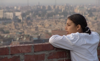 Menina do alto de uma construção olhando a vista do Oriente Médio.