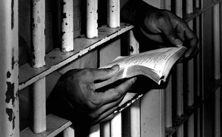 Homem lê bíblia na prisão